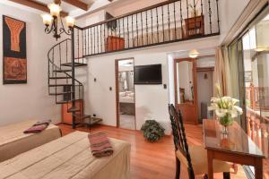 a living room with a table and a spiral staircase at Hotel Ruinas in Cusco