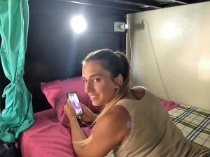 une femme posant sur un lit tenant un téléphone portable dans l'établissement Costa Rica Backpackers, à San José