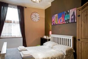 a bedroom with a bed and a clock on the wall at Oaklands (Self Check-in) in Wolverhampton