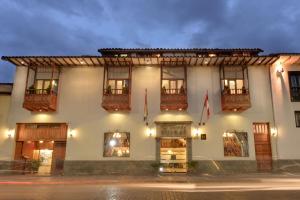 un gran edificio blanco con ventanas y banderas. en Hotel Ruinas, en Cusco