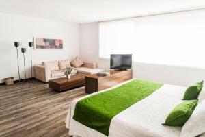 a bedroom with a bed and a couch and a television at Hotel Bogota Virrey in Bogotá