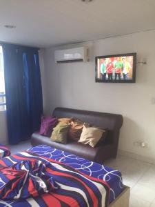 a bedroom with a couch and a tv on the wall at Apartamento en Cartagena, cerca al mar, edificio Nuevo Conquistador in Cartagena de Indias