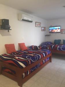 two beds in a room with a tv on the wall at Apartamento en Cartagena, cerca al mar, edificio Nuevo Conquistador in Cartagena de Indias