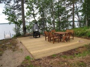 a wooden deck with a table and chairs next to the water at Matila's Cottages in Sumiainen