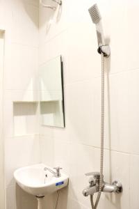 a white bathroom with a sink and a shower at House of Dharmawan in Surabaya