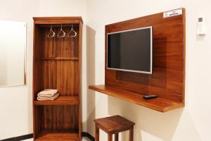 a flat screen tv on a wall with a shelf at House of Dharmawan in Surabaya