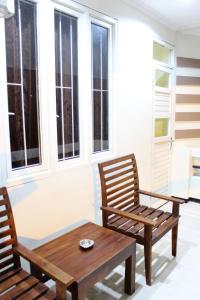two chairs and a coffee table on a porch with windows at House of Dharmawan in Surabaya