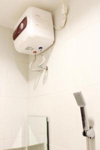 a shower in a bathroom with a hair dryer on the wall at House of Dharmawan in Surabaya