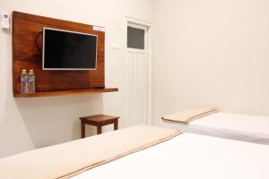 a bedroom with two beds and a tv on a wall at House of Dharmawan in Surabaya