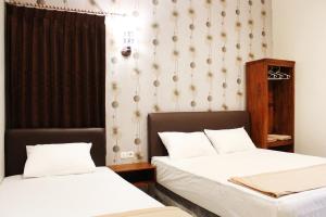 a bedroom with two beds and a wall at House of Dharmawan in Surabaya