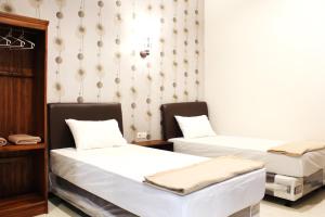 a room with two beds and a wall with a wallpaper at House of Dharmawan in Surabaya