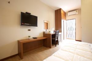 Habitación con cama, escritorio y TV en la pared. en 777 Food & Bed en Chiang Rai