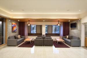 eine Lobby mit Sofas, Sesseln und einem Fernseher in der Unterkunft The Eastern Hotel in Ankleshwar