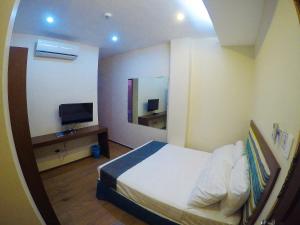 a hotel room with a bed and a television at Golden Gate Suites in Dumaguete