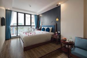 a bedroom with a large bed and a blue chair at Holiday Emerald Hotel in Hanoi