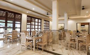 a dining room with tables and chairs and windows at Vila Ombak in Gili Trawangan
