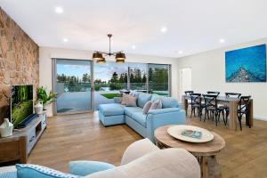 a living room with a blue couch and a table at Belle Vue- Penthouse at Black Beach in Kiama