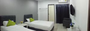 a hotel room with two beds and a chair at The Clover Lampang in Lampang