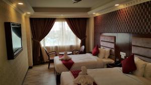 a hotel room with two beds and a television at Hyders Park The Business Hotel in Thanjāvūr