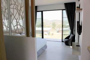 um quarto com uma cama e uma grande janela de vidro em Phurapee Pakchong em Ban Lam Thong Lang