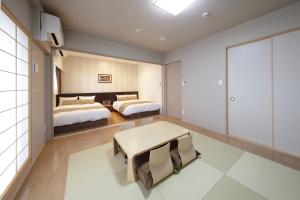 a bedroom with two beds and a table at SARASA HOTEL Shinsaibashi in Osaka