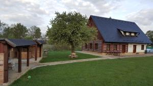 a large wooden house with a tree in the yard at Pension Konírna in Huntířov