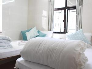 1 cama con edredón blanco y almohadas en una habitación en New Yan Yan Guest House reception 9th floor Flat E4 E6, en Hong Kong