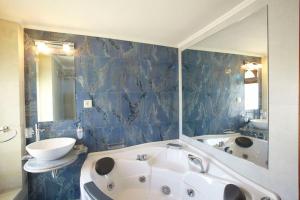 ein blau gefliestes Bad mit einer Badewanne und einem Waschbecken in der Unterkunft Casa dell' Aristea in Atsipopoulo