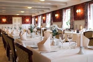 a dining room with white tables and chairs with white flowers at Tambohus Kro & Badehotel in Hvidbjerg