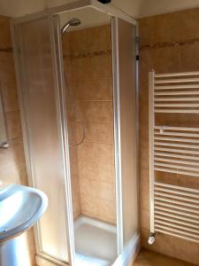 una doccia con una porta in vetro accanto a un lavandino di La Nuvola sul Mare a Vara Superiore