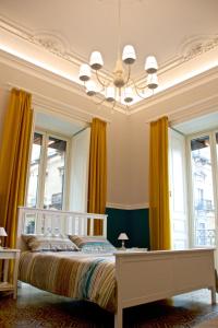 a bedroom with a bed with yellow curtains and a chandelier at B&B Umberto 134 in Catania