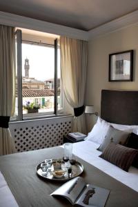 Una habitación de hotel con una cama con una bandeja de comida. en Tornabuoni Suites Collection Residenza D'Epoca en Florencia