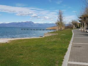 a road next to a body of water with a pier at Affittacamere Porticciolo in Castelnuovo del Garda