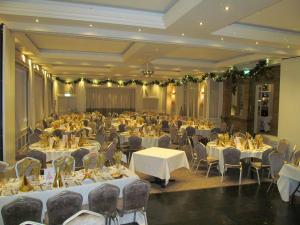 una sala de banquetes con mesas y sillas blancas y una habitación en Best Western The Shrubbery, en Ilminster