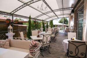 un restaurante con mesas y sillas blancas y techo de cristal en семеен хотел Прованс Ахелой, en Aheloy
