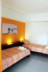 アルブフェイラにあるAcoteias Beach Studioのオレンジ色の壁の客室内のベッド2台