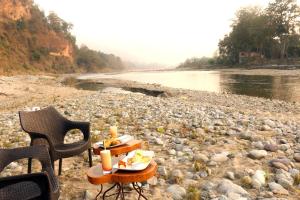 a table with food and candles on a rocky beach at Riverside By Aahma-Fully Vaccinated Staff in Garjia