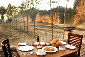 een houten tafel met eten en uitzicht op een rivier bij Riverside By Aahma in Garjia