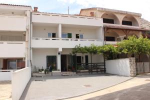 a white house with a courtyard in front of it at Apartments Mostak in Baška