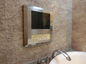 a bathroom with a television on a tiled wall at Hotel Hyper Noah (Adult Only) in Sakai