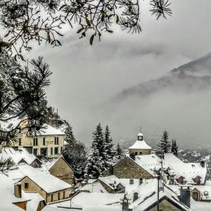 una ciudad cubierta de nieve con una iglesia al fondo en Hotel Mariana, en Tramacastilla de Tena