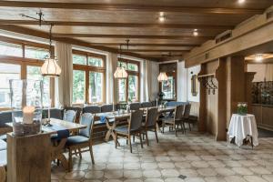 a dining room with tables and chairs and windows at Gästehaus Becher in Donzdorf