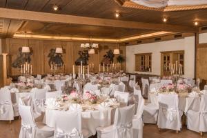 une salle remplie de tables et de chaises blanches avec des fleurs dans l'établissement Gästehaus Becher, à Donzdorf