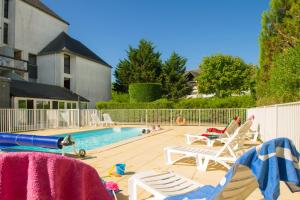 una piscina con 2 sillas de césped y una piscina en Résidence Goélia Bleue Océane, en Carnac