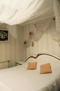 a bedroom with a white bed with white curtains at Gusarskiy Hotel and Apartment in Kyiv
