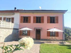 uma casa cor-de-rosa com dois guarda-chuvas à frente. em Agriturismo La Ferriera em Pignone