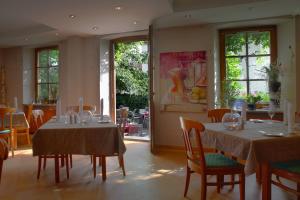 una sala da pranzo con due tavoli, sedie e finestre di Landgasthof zur Brücke a Wiesentheid