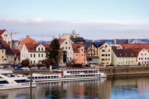 a group of boats docked in a river with buildings at Donaupromenade in Regensburg