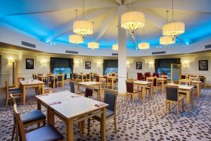 a dining room with tables and chairs and chandeliers at Leonardo Hotel Inverness in Inverness