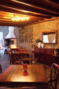 un restaurante con una mesa y sillas de madera y una pared de piedra en Summer Time - Tinos Apartments, en Agios Sostis